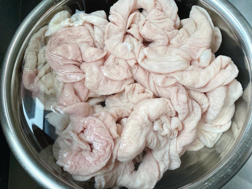Drain the intestines. Add 3 tablespoons of salt and 3 tablespoons of Shaoxing wine. Knead vigorously one last time. This combination acts as a powerful deodorizer. Rinse thoroughly until the water is completely crystal clear.