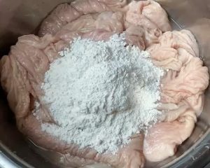 Place the unwashed intestines in your large basin. Add 2 tablespoons of flour. Begin kneading and rubbing the flour into the surface. The flour will clump as it absorbs the thick mucus. If it feels too dry, add a tiny splash of water.