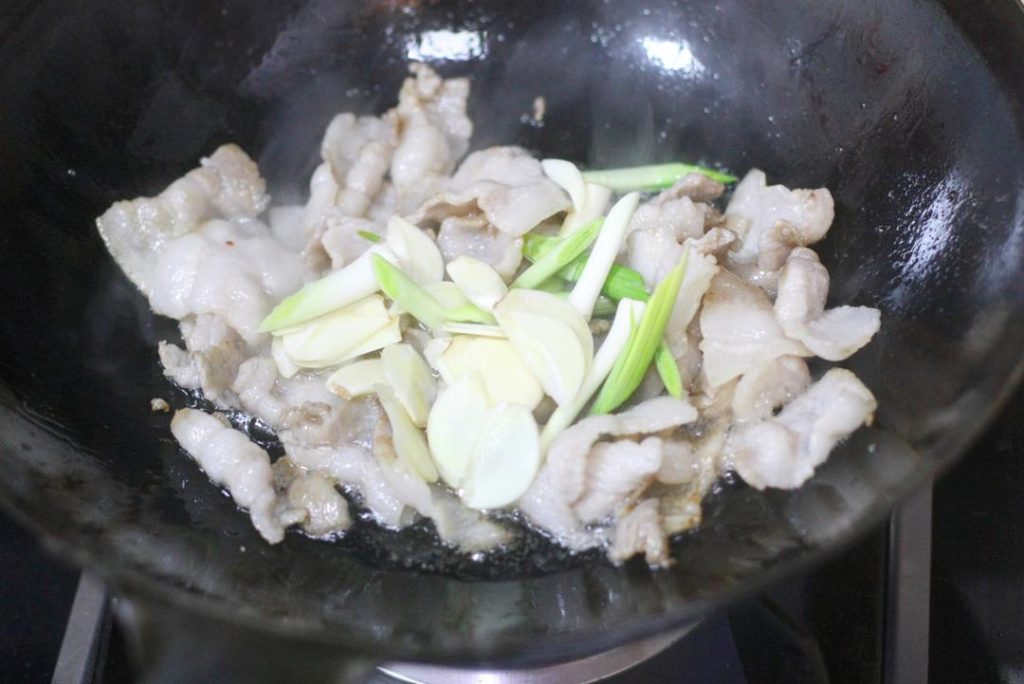Aromatics Add the sliced garlic and the white parts of the garlic sprouts/leeks. Stir-fry for about 30 seconds until fragrant.