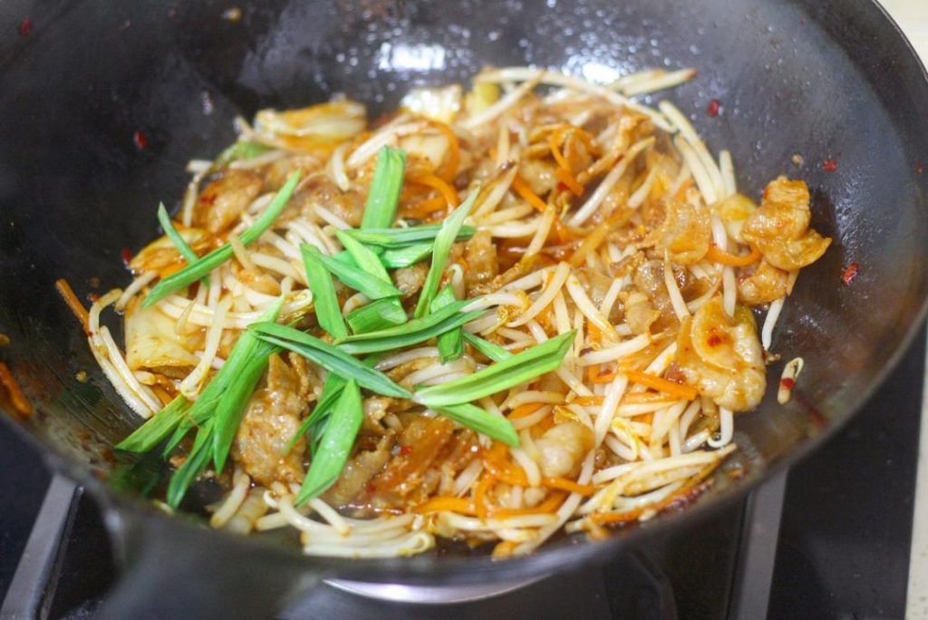 Finish Add a pinch of Salt and Sugar to taste. Finally, toss in the green parts of the garlic sprouts. Give it a few quick turns to wilt the greens, then immediately remove from heat and serve.