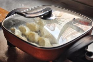 Immediately cover with a lid. The water will boil and create steam, cooking the dough and the raw meat filling. Keep the heat on medium-high. Listen to the sound; vigorous bubbling means it is cooking.