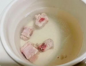 Execute the Lazy Blanching Method: Place your raw pork rib segments into your cooking pot. Pour freshly boiled water over them. Use chopsticks to stir the ribs vigorously for about 30 seconds. You will see the water turn cloudy as blood and impurities seep out.