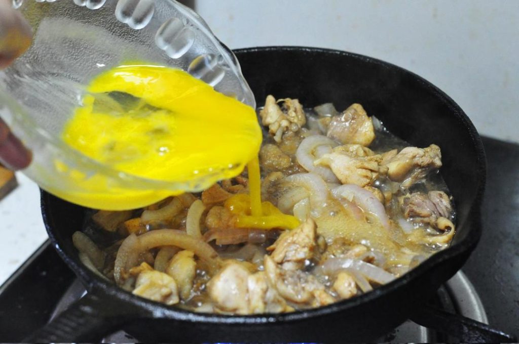 First Egg Pour: Lower the heat to a simmer. Pour half of the egg mixture over the chicken and onions in a circular motion. Cover the pan with a lid and cook for about 30 seconds. This creates a stable base.