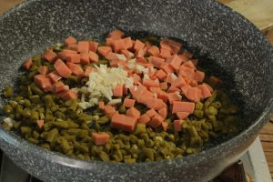 Sauté the Aromatics Heat your wok or skillet over medium-high heat. Add 1 tablespoon of neutral oil. Once hot, add the pickled bean dice, ham cubes, and minced garlic. Stir-fry for about 2–3 minutes.