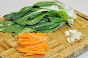 Prep Vegetables Wash the bok choy and carrots. Cut the carrots into thin matchsticks (julienne) so they cook at the same rate as the pork. Slice the garlic.