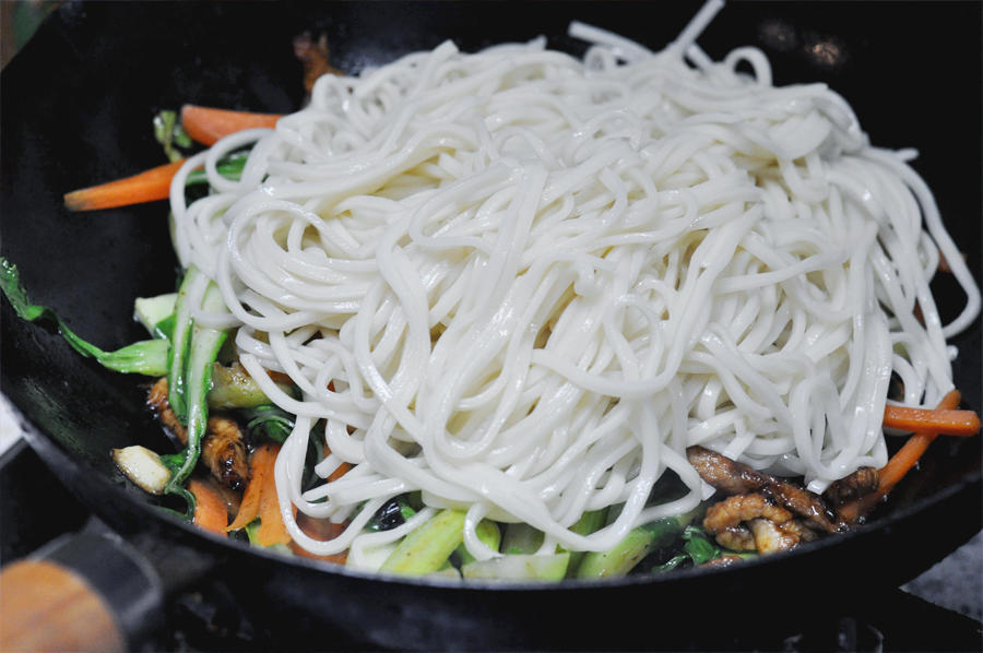 Cook Vegetables and Combine Add another tablespoon of oil to the wok. Add the garlic, carrots, and bok choy stems (save the leaves for later if you want them crisp). Stir-fry for 1 minute until softened. Add the noodles and the cooked pork back into the pan.