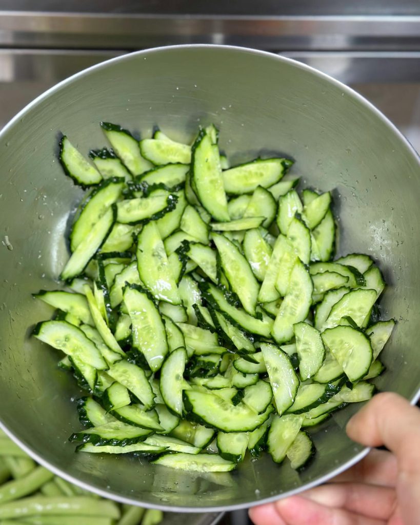 Prep the Cucumber (The Most Important Step) Slice the cucumber in half lengthwise, then cut diagonally into thin slices (approx 1/8 inch thick). Place in a large bowl and toss with 1 tablespoon of salt.