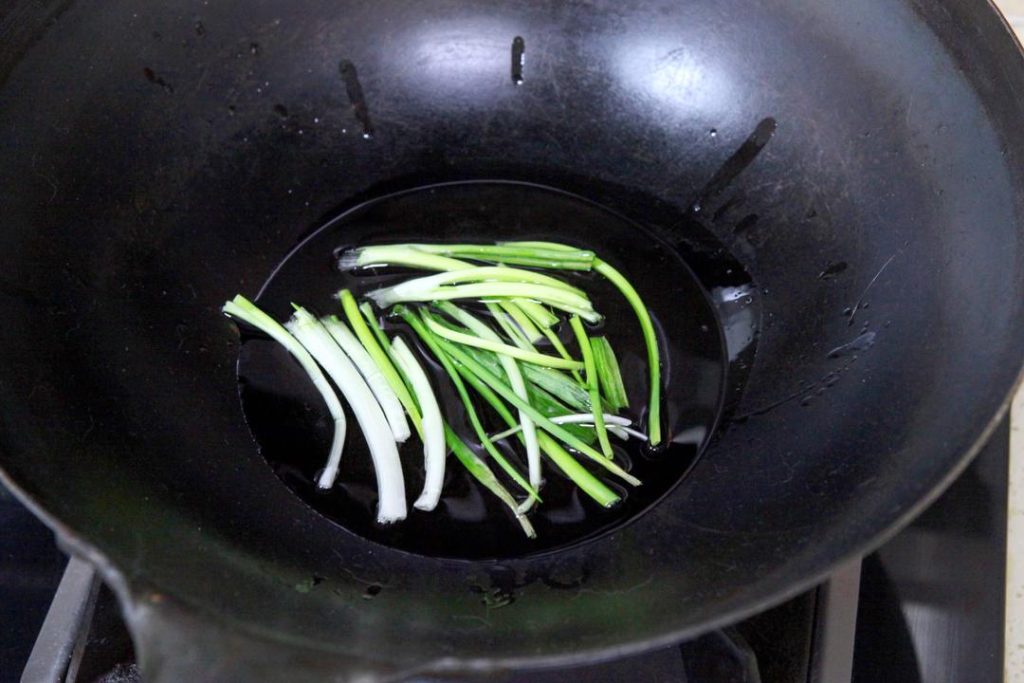 Infuse the Oil Heat your wok or small pot over medium heat. Add the 4 tablespoons of salad oil. Add the scallion segments. Fry them slowly until they turn golden brown and dry out. This infuses the oil with onion flavor. Use chopsticks to remove and discard the scallions, leaving the aromatic oil behind.