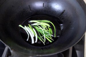 Infuse the Oil Heat your wok or small pot over medium heat. Add the 4 tablespoons of salad oil. Add the scallion segments. Fry them slowly until they turn golden brown and dry out. This infuses the oil with onion flavor. Use chopsticks to remove and discard the scallions, leaving the aromatic oil behind.