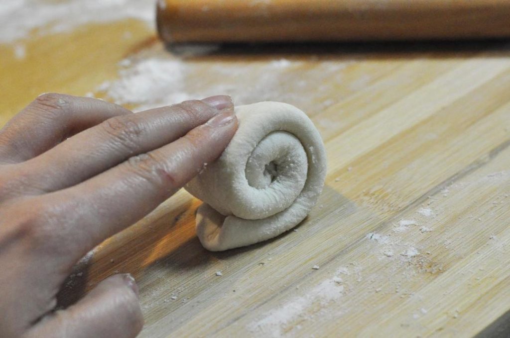 Form the "Snail": Take a portion of dough and roll it into a long, thin rope or strip. Flatten this strip with a rolling pin. Fold the strip in half lengthwise, then roll it up from one end like a snail shell or cinnamon roll. Tuck the tail end underneath.