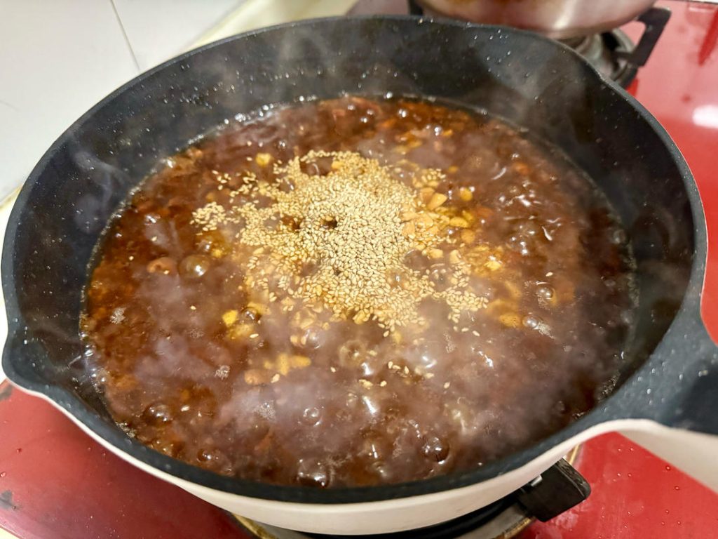 Turn off the heat (or turn to the lowest setting). Stir in the crushed peanuts and toasted sesame seeds. The residual heat will release their nutty aroma without burning them.