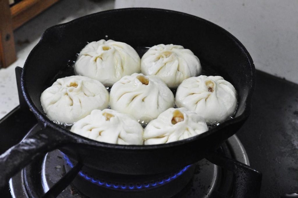 The Fry-Steam Method: Heat a tablespoon of oil in a flat pan over medium heat. Arrange the buns in the pan (pleat side up or down, though pleat-down is common for Sheng Jian Bao to get a crispy top, this recipe implies pleat-up presentation).