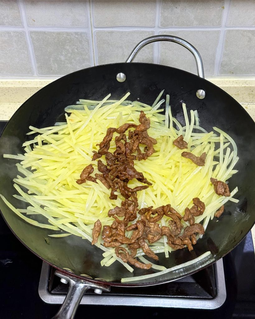 Add the cooked pork back into the pan with the potatoes. Toss to combine. Pour in the 1 tbsp Light Soy Sauce, 2 tsp Oyster Sauce, salt, and chicken essence.