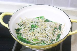 Stir-fry the Vegetables Heat a little oil in the wok. Stir-fry the leafy greens and bean sprouts until just wilted (断生 - duan sheng). Do not overcook; they should remain crunchy. Transfer them to the bottom of your serving bowl.