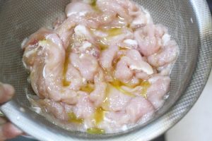 Add salt, white pepper, 1 tsp light soy sauce, and Shaoxing wine. Mix well with your hand until the liquid is absorbed. Add the egg white and potato starch. Mix vigorously until the pork feels sticky. Finally, add a teaspoon of oil to coat the meat (this prevents sticking later). Cover and let rest for 20-30 minutes.