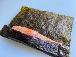 Wrap the Fish (5 mins): Lay out a sheet of sushi nori. Place a salmon strip at one edge. Roll the nori around the fish to create a single overlapping layer.