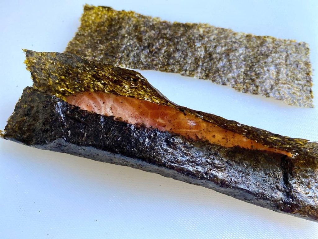 Seal the Nori (2 mins): Trim off any excess seaweed with kitchen shears. Dip your finger in water and lightly run it along the edge of the nori to glue it shut. Pinch the ends slightly to seal the packet.