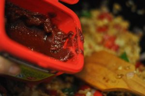 Season with Gochujang Add one large tablespoon of Korean Gochujang paste. Stir-fry vigorously to ensure the paste coats every grain of rice evenly.