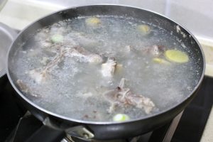 Blanch the Lamb Place the soaked lamb spine into a pot of cold water. Add a splash of cooking wine, a few slices of ginger, and a scallion segment. Bring to a boil over high heat.