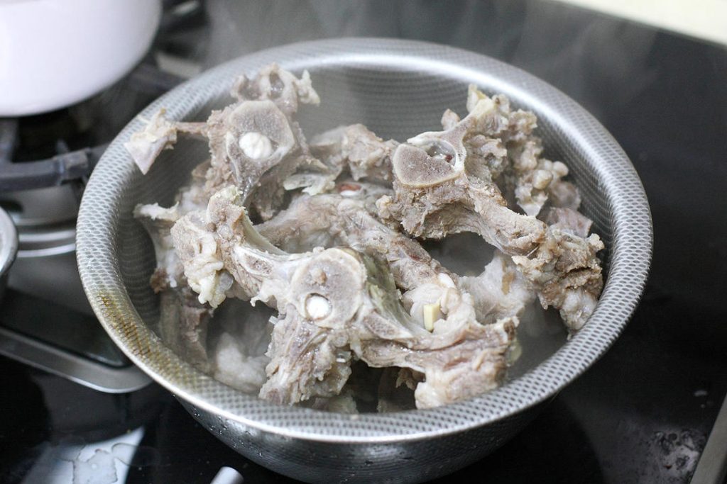 Blanch the Lamb
Place the soaked lamb spine into a pot of cold water. Add a splash of cooking wine, a few slices of ginger, and a scallion segment. Bring to a boil over high heat.
