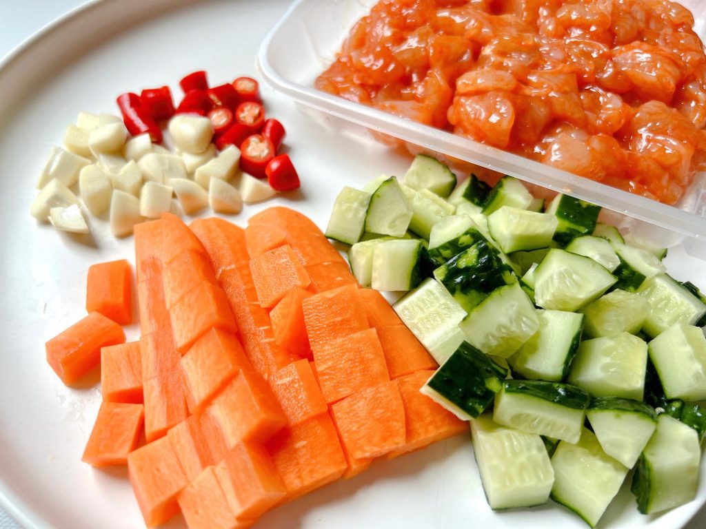 Peel the carrot and dice it into small, uniform cubes. Scrape or peel the cucumber and dice it to match the carrot's size. Mince the garlic and slice the Thai chilies into small rings.
