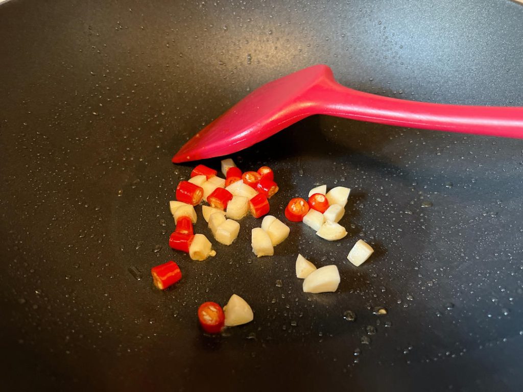 Sauté Aromatics: In the same pan (add a drop more oil if dry), add the minced garlic and sliced chilies. Stir-fry for 15 seconds until highly fragrant.