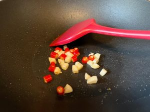 Sauté Aromatics: In the same pan (add a drop more oil if dry), add the minced garlic and sliced chilies. Stir-fry for 15 seconds until highly fragrant.
