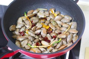 Immediately dump the drained clams into the wok. Toss rapidly for 10-15 seconds to coat the shells in the aromatic oil and soy sauce.