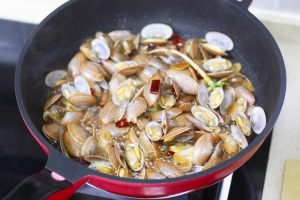 Cover the wok with a lid. Keep the heat on High. Let it steam for 1 minute 30 seconds to 2 minutes. The clams will release their natural juices, creating steam that opens the shells and cooks the meat gently.