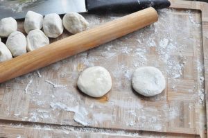 Portion the Dough Roll the dough into a long log and cut it into equal-sized pieces (about the size of a golf ball or slightly smaller). Press each piece down with your palm to make a small disc (a "ji zi").