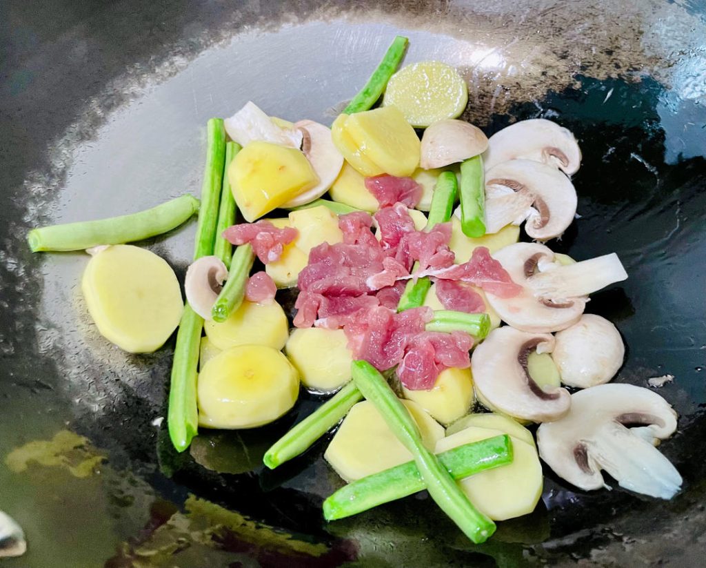 Stir-Fry the Base: Immediately add the sliced pork, potatoes, green beans, and mushrooms to the wok. The oil temperature should be around 325°F (165°C). Stir-fry constantly for about 1 to 2 minutes. Watch for the pork to change color and no longer look raw.