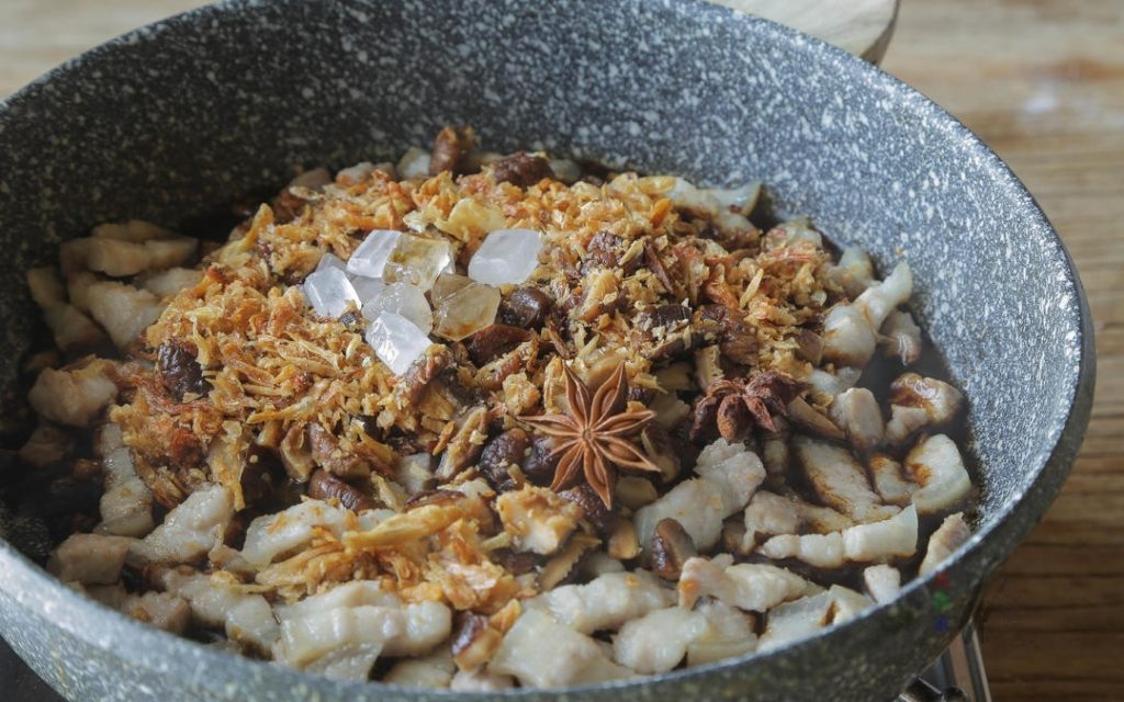 Aromatics Add the diced shiitake mushrooms, fried shallots, rock sugar, and Star Anise to the pork in the pot. Stir-fry everything together until fragrant and the sugar begins to melt.