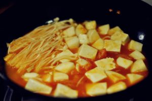 Cook Vegetables Add the cubed tofu, King Oyster mushrooms, and Enoki mushrooms. Simmer for 3-4 minutes until the mushrooms are tender.