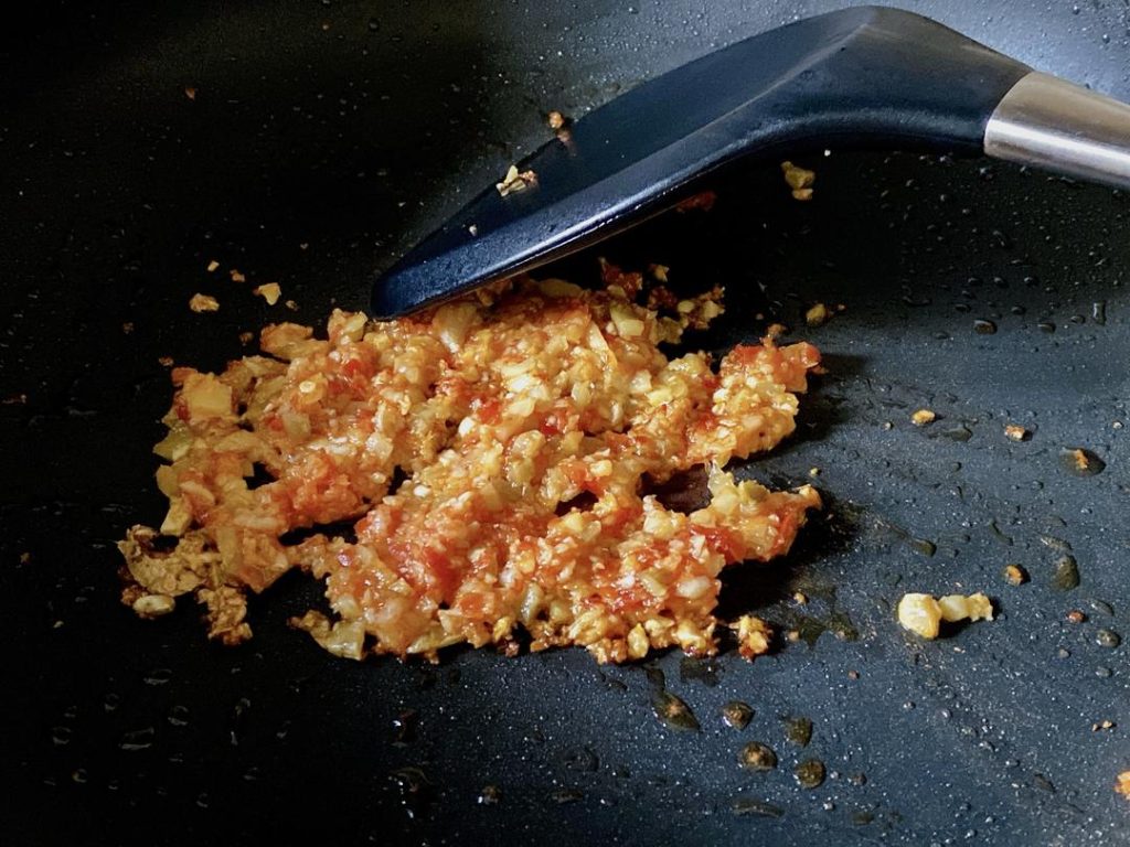 Bloom the Spices: Add the chopped Zha Cai and chili sauce to the garlic. Sauté for another 30 seconds until the red oil releases and smells aromatic.