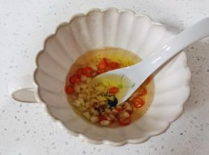 Aromatic Prep: Mince the garlic and slice the chilies. Place them in a heat-proof bowl.
