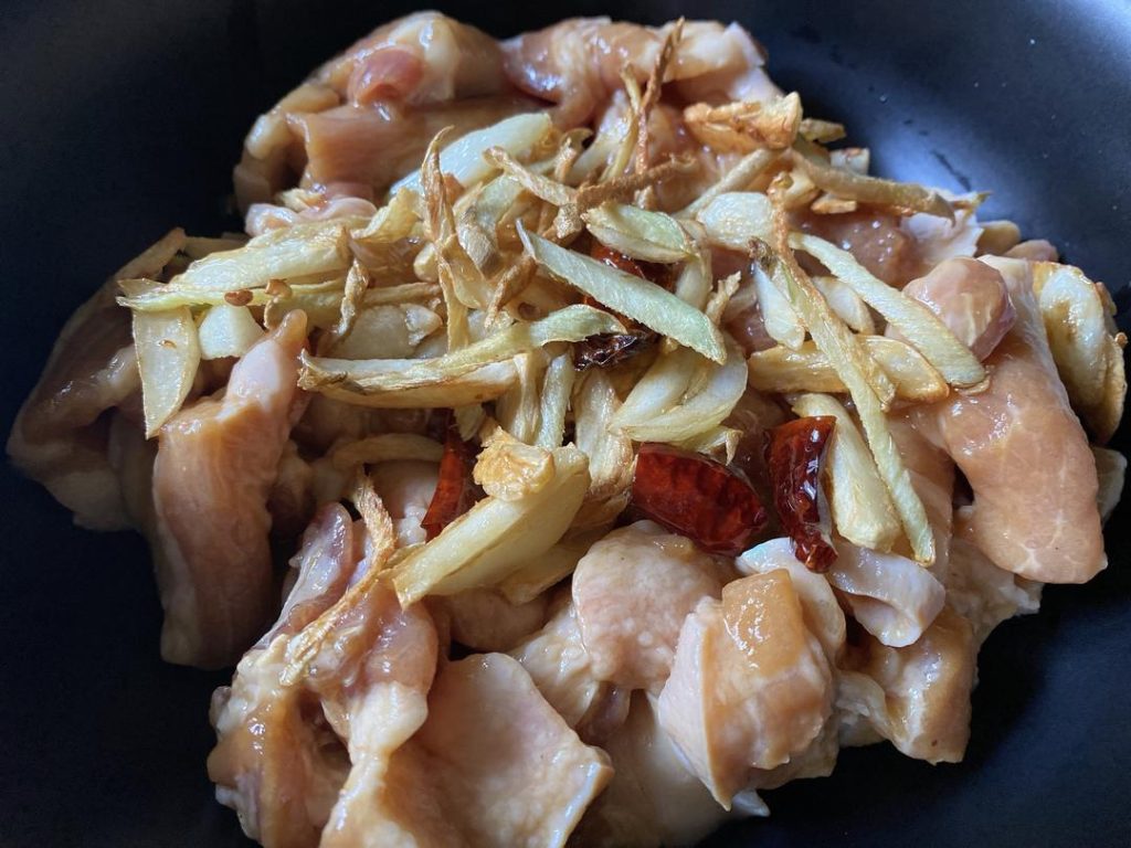 Combine and Marinate: Pour the hot aromatic oil, along with the fried ginger, garlic, and chilies, directly into the marinated pork. Mix well. Cover and refrigerate for 30 minutes.