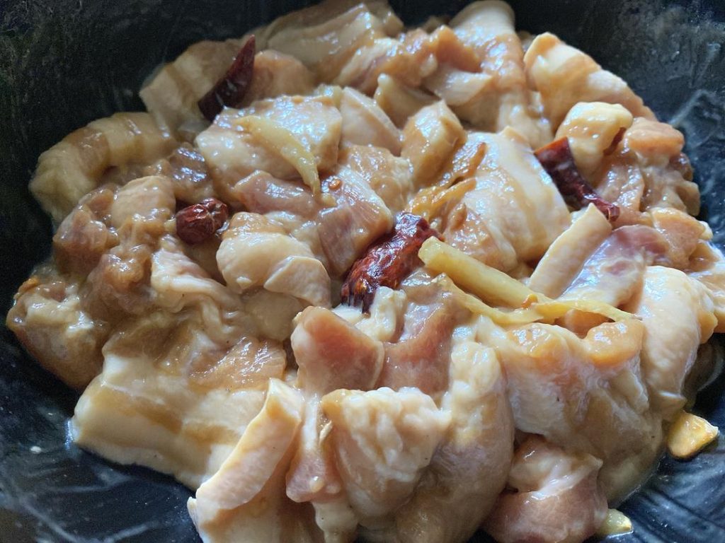 Combine and Marinate: Pour the hot aromatic oil, along with the fried ginger, garlic, and chilies, directly into the marinated pork. Mix well. Cover and refrigerate for 30 minutes.