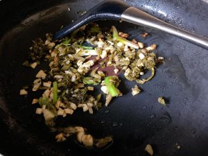 For Method 1: Heat 1 tbsp of oil in your wok over medium heat. Sauté the garlic and the white parts of the scallions (or chive stems) until fragrant. Toss in the pickled mustard greens and stir-fry for 30 seconds.