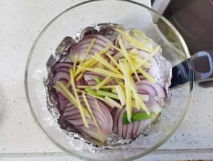 Layer the Base: Line your air fryer basket with foil. Scatter the majority of the sliced onions and half of the ginger, garlic, and scallion whites onto the bottom.