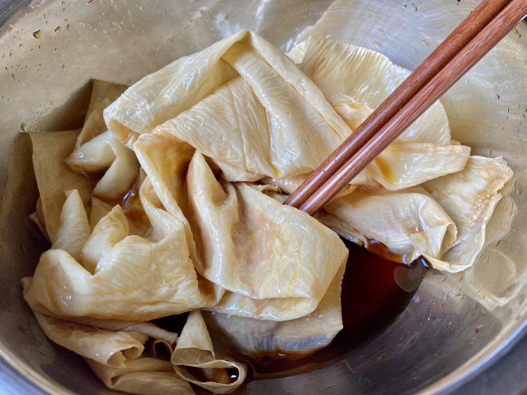 Wrap the Rolls: Cut the 2 large tofu skin sheets in half to create 4 semi-circles.