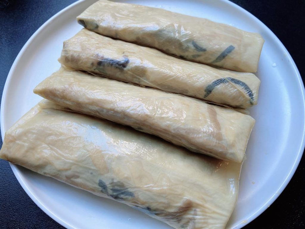 Wrap the Rolls: Cut the 2 large tofu skin sheets in half to create 4 semi-circles.