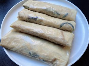 Wrap the Rolls: Cut the 2 large tofu skin sheets in half to create 4 semi-circles.