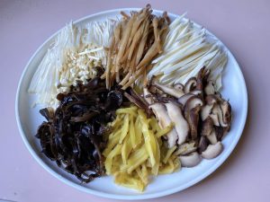 Julienne: Peel the water bamboo. Thinly julienne the water bamboo, rehydrated wood ear mushrooms, Zha Cai, and shiitake mushrooms. Cut the enoki mushrooms into 2-inch sections.