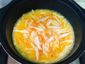 Adding crab sticks and boiling water to the egg base