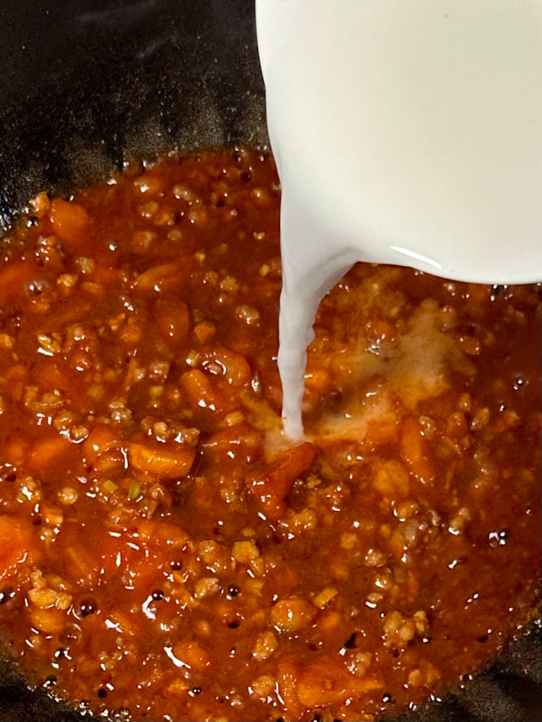 Pouring cornstarch slurry to thicken the sauce