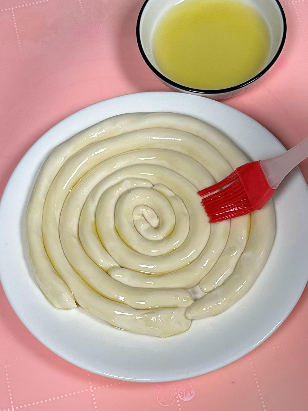 Coiling oiled dough strips on a plate