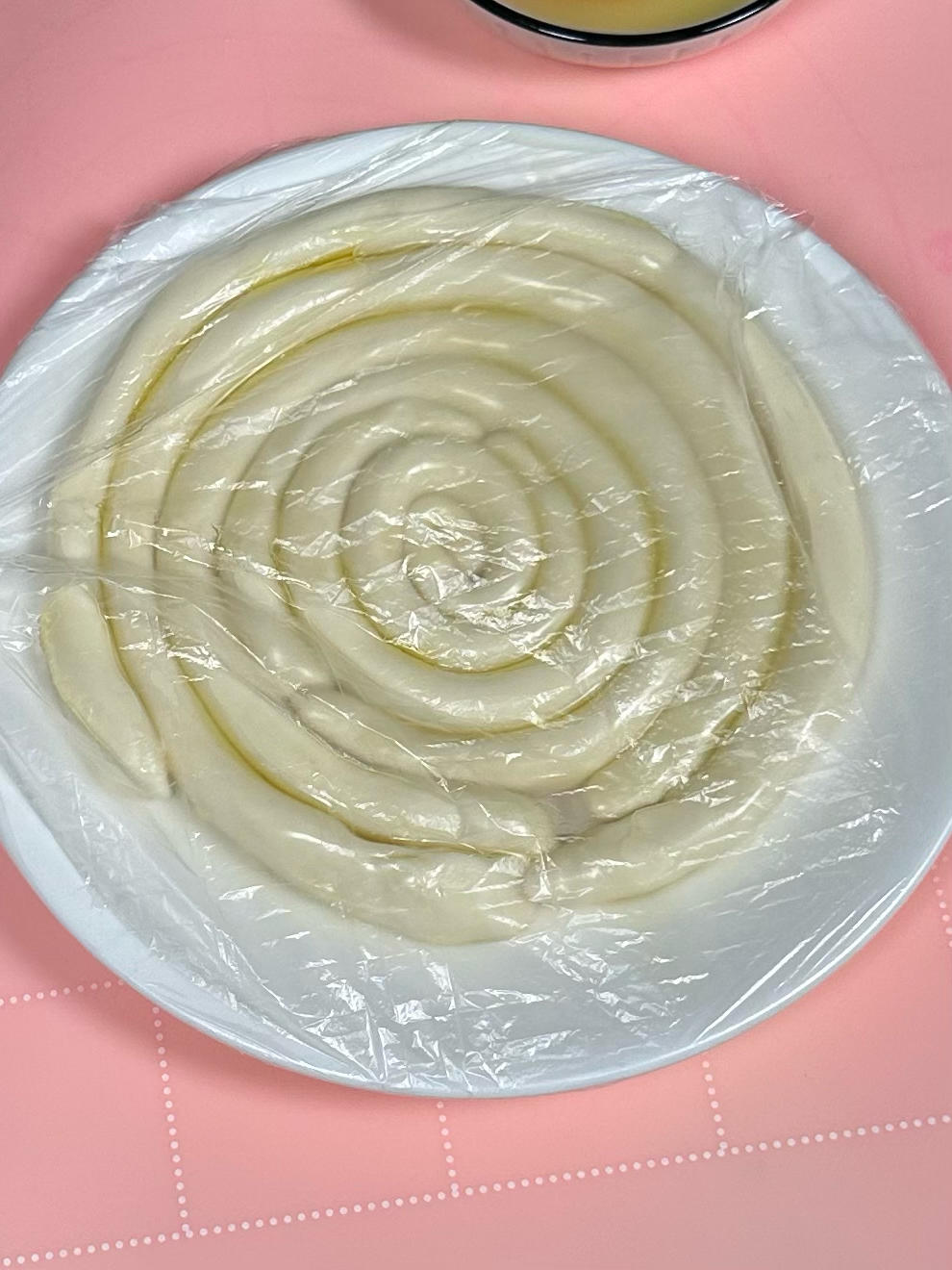 Covering dough with plastic wrap to rest