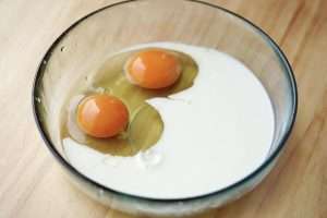Crack 2 eggs into a bowl, add 100 ml of milk, and whisk until smooth.