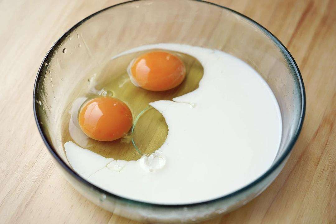 Crack 2 eggs into a bowl, add 100 ml of milk, and whisk until smooth.
