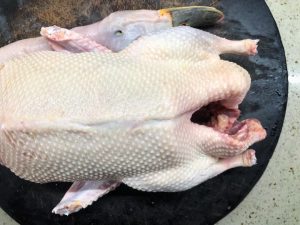 Clean the duck, remove the feet and wing tips, and pat it completely dry